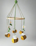 Crocheted baby mobile with bumblebees, daisies hanging from wooden ring on green strings