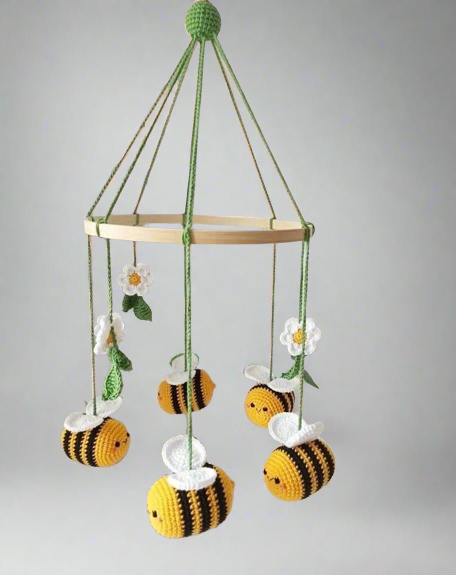 Crocheted baby mobile with bumblebees, daisies hanging from wooden ring on green strings