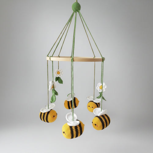 Crocheted baby mobile with bumblebees, daisies hanging from wooden ring on green strings