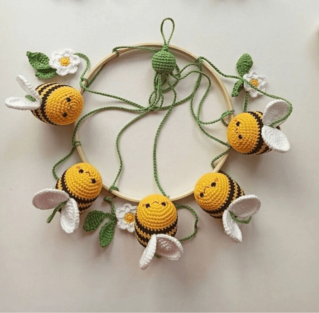 Crocheted bumblebees and white flowers arranged in a circular wooden hoop wreath