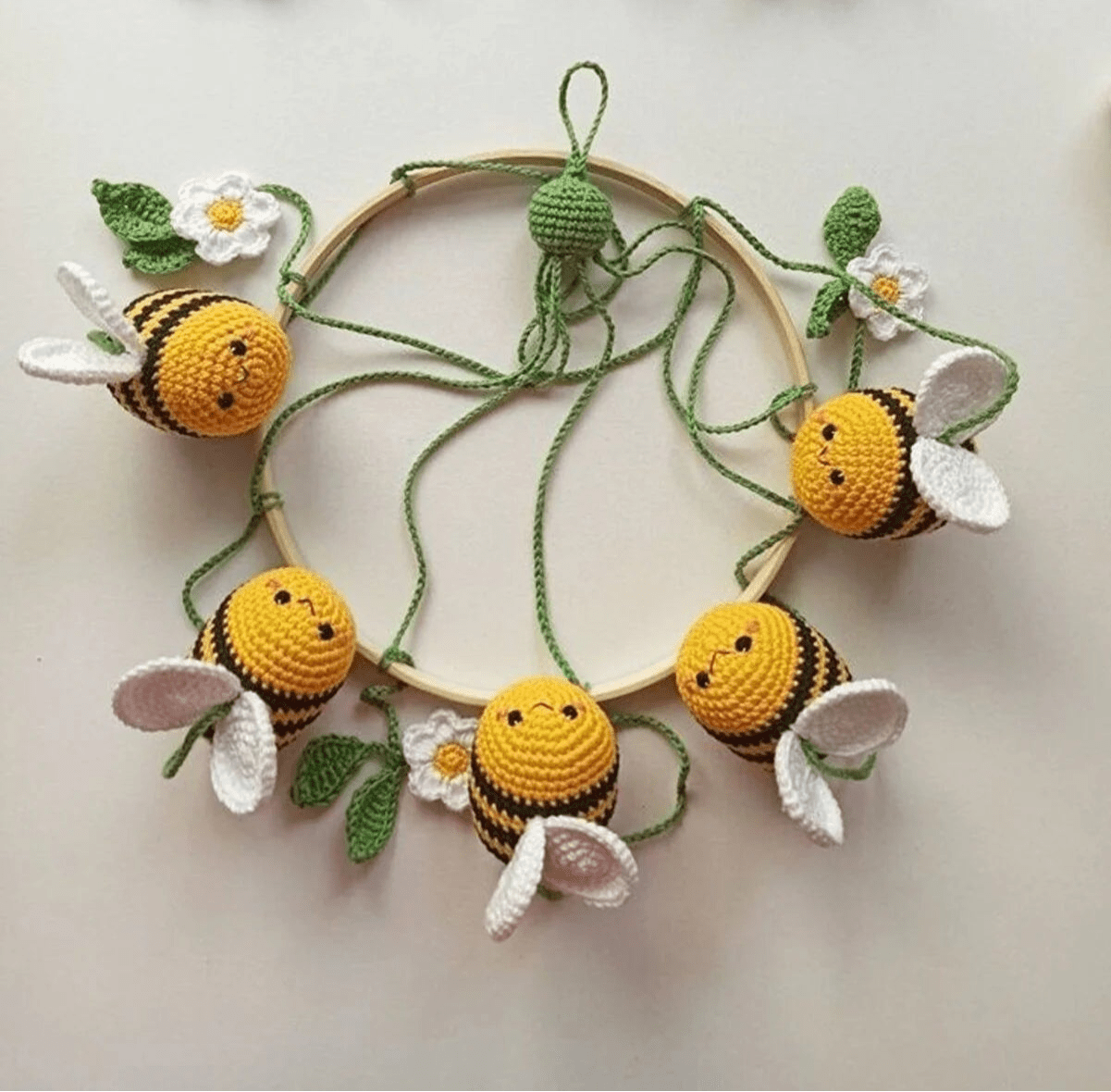 Crocheted bumblebees and white flowers arranged in a circular wooden hoop wreath