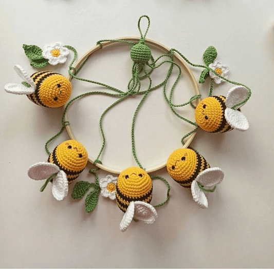 Crocheted bumblebees and white flowers arranged in a circular wooden hoop wreath