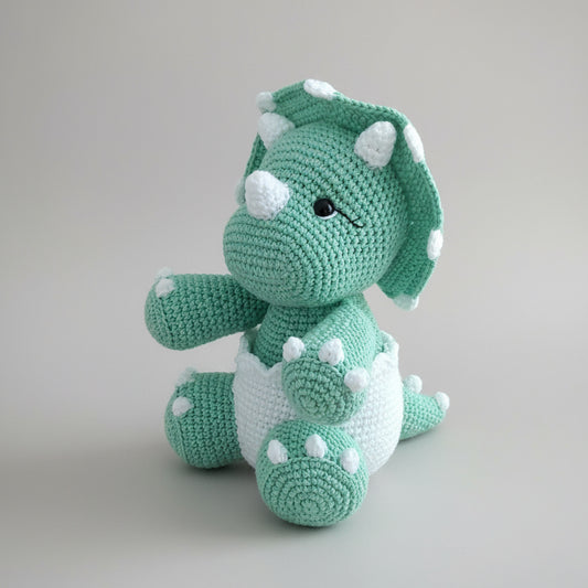 Crocheted green and white triceratops stuffed animal with white bumps