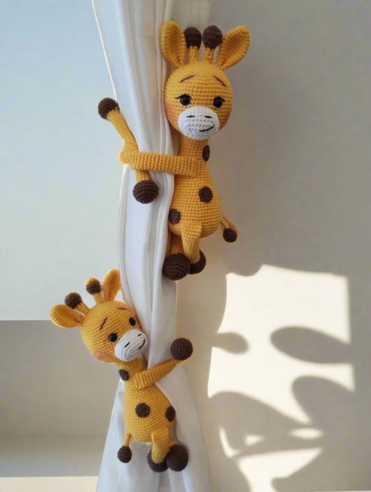 Two crocheted yellow giraffes hugging a white curtain, with playful shadows behind them