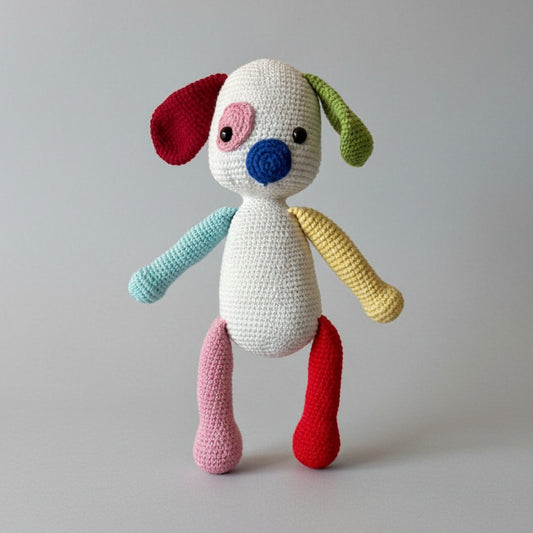 Crocheted stuffed dog with colorful mismatched limbs: red, green, yellow, blue, pink, and white body