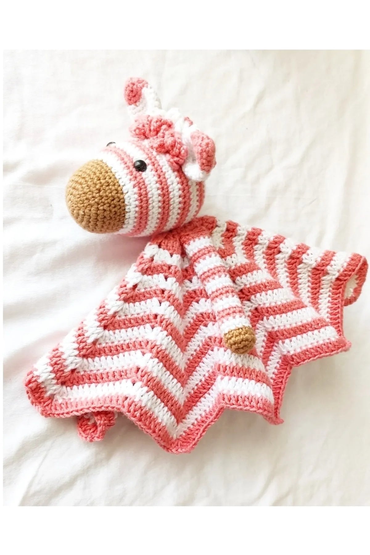 Crocheted pink and white striped lovey security blanket with zebra head and wooden rattle