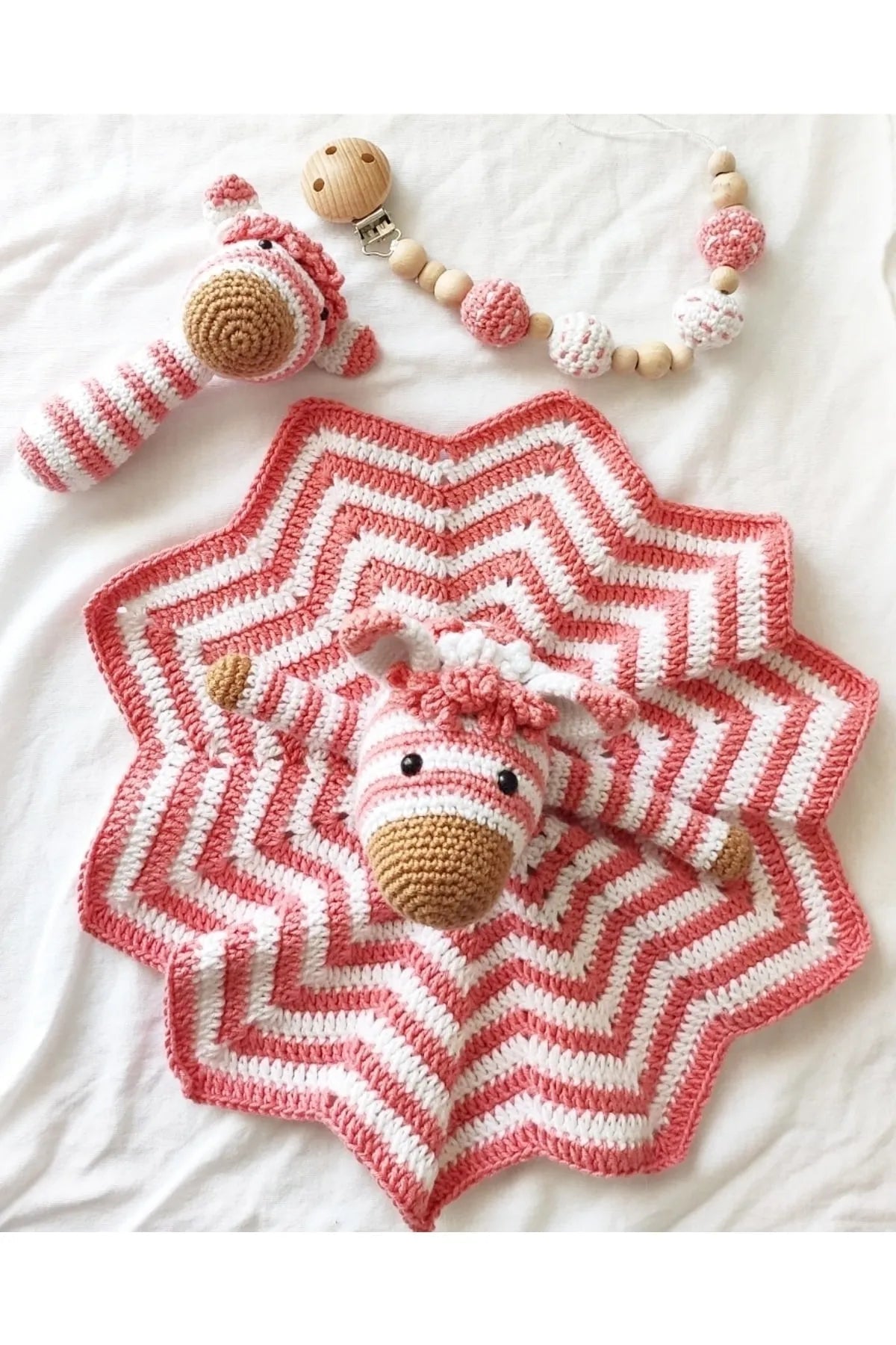 Crocheted pink and white star-shaped baby blanket with matching unicorn rattle and teething toy