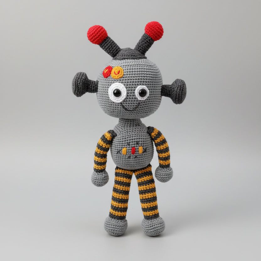 Crocheted robot toy with red antenna and striped yellow-gray limbs, smiling with white eyes