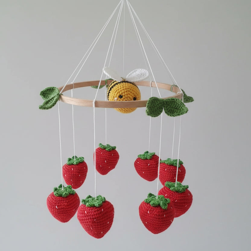 Crocheted bee mobile with strawberries hanging from wooden circle, handmade nursery decor
