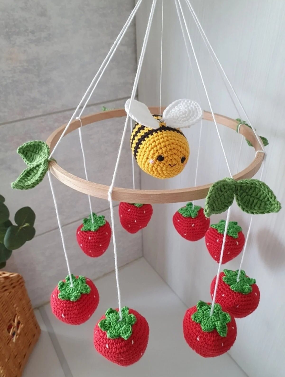 Crocheted bee mobile with strawberries hanging from wooden circle, handmade nursery decor