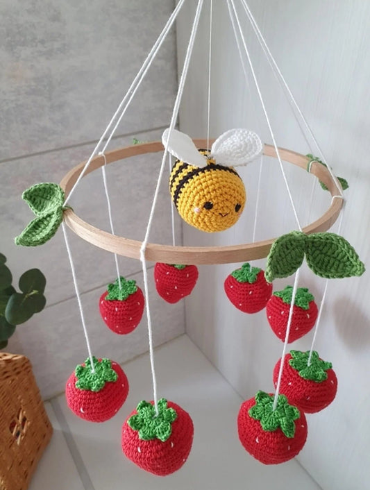 Crocheted bee mobile with strawberries hanging from wooden circle, handmade nursery decor